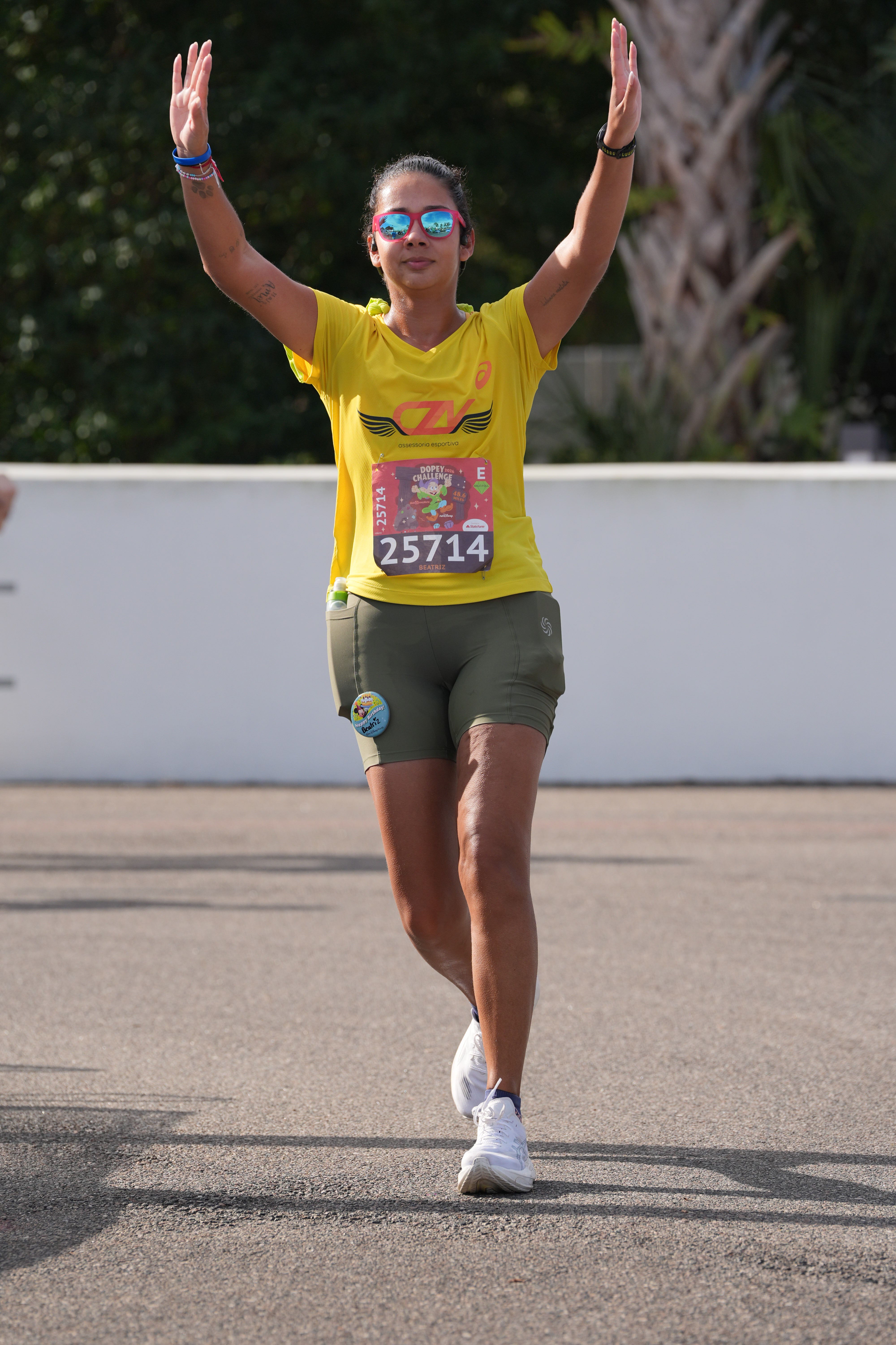 Beatriz da Talla Turismo durante uma corrida da runDisney no Walt Disney World, em Orlando, com os braços erguidos em comemoração. A imagem transmite a emoção e a conquista de completar uma prova das corridas Disney.