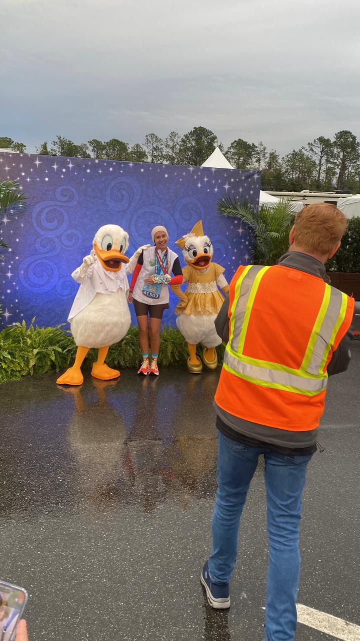 Fotógrafo oficial do Disney PhotoPass registrando corredora da runDisney com Donald e Daisy Duck ao final do percurso de uma corrida Disney em Orlando.