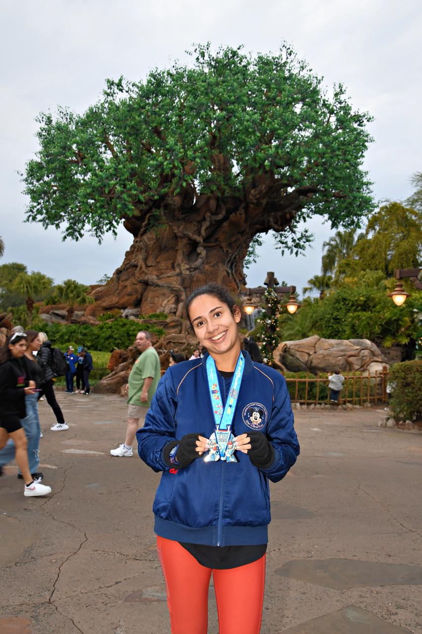 Corredora exibindo medalhas da runDisney em frente à Árvore da Vida, no Disney's Animal Kingdom, durante viagem para participar das corridas Disney em Orlando