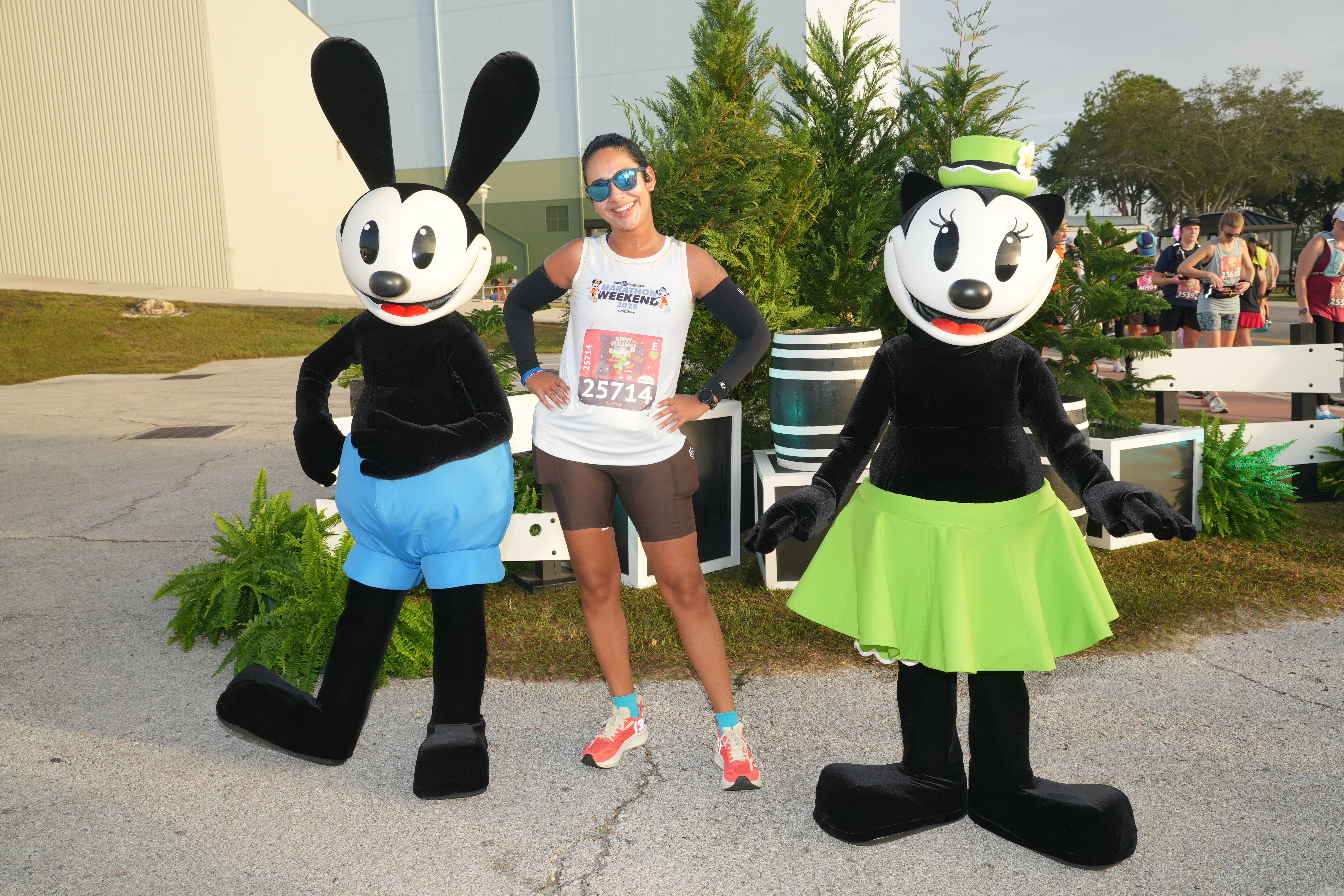 Corredora da runDisney posa com Oswald e Ortensia durante uma corrida Disney no Walt Disney World, em um ponto de foto com personagens no percurso