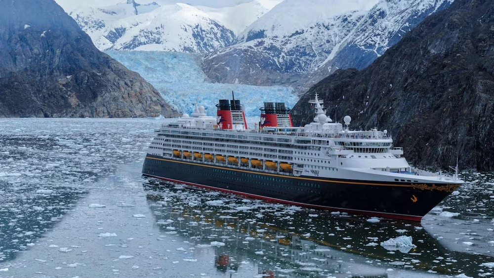 Disney Magic navegando pelo Alasca, cercado por águas com blocos de gelo, montanhas nevadas e geleira ao fundo