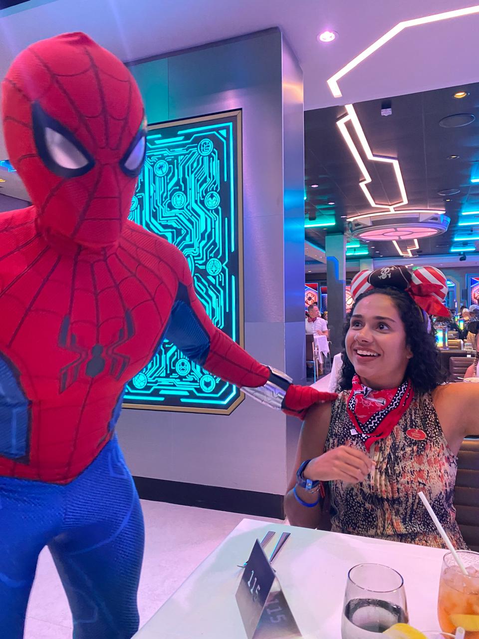 Beatriz da Talla Turismo durante jantar temático com personagem Spider-Man no cruzeiro Disney, em restaurante imersivo a bordo da Disney Cruise Line.
