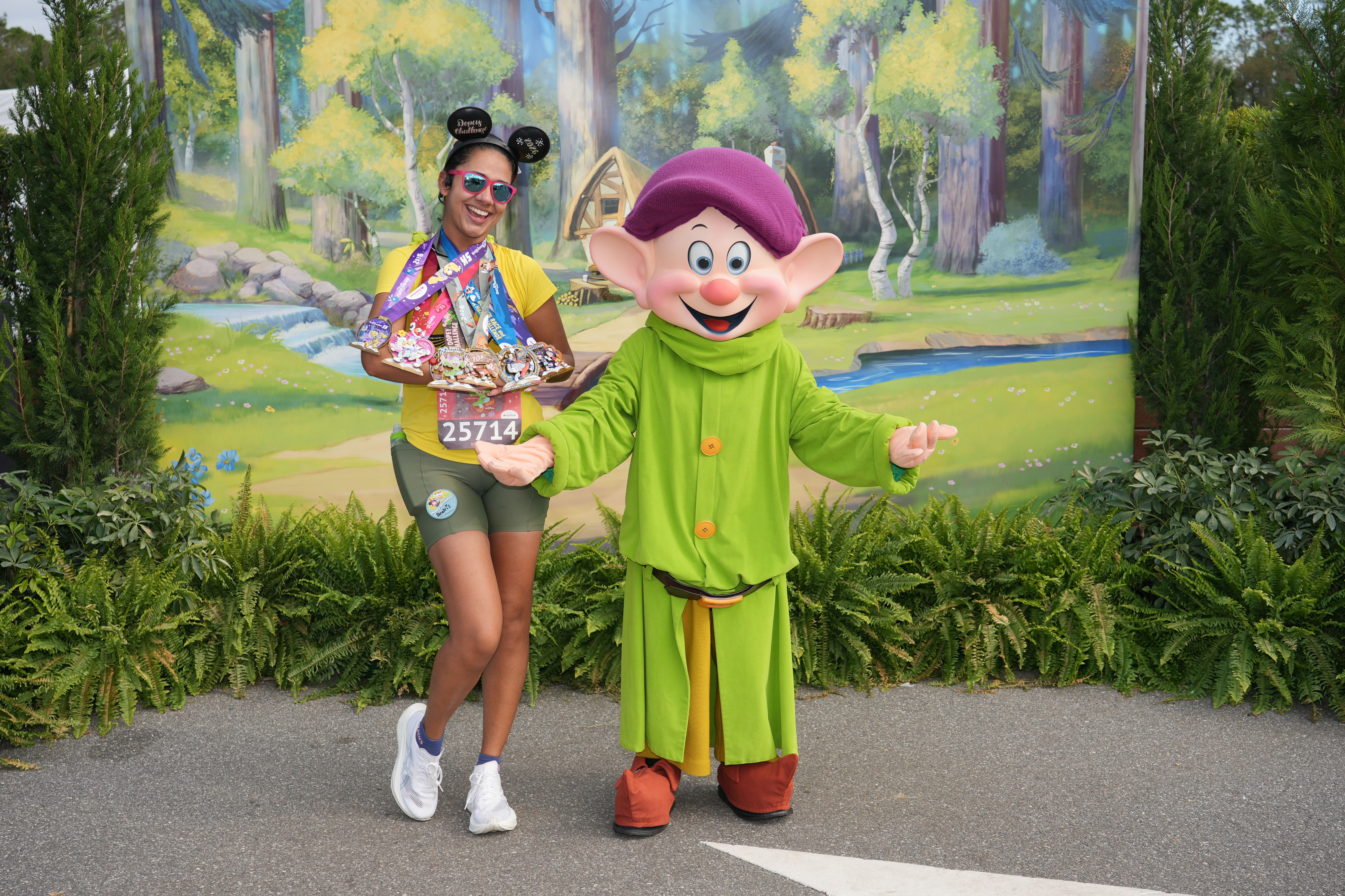 Beatriz, da Talla Turismo, posa com o personagem Dunga durante a Walt Disney World Marathon Weekend 2026, exibindo as medalhas conquistadas na experiência runDisney em Orlando.