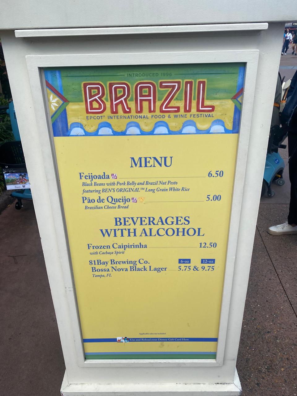 Menu do quiosque do Brasil no EPCOT International Food & Wine Festival com feijoada, pão de queijo e caipirinha, representando a culinária brasileira no festival gastronômico da Disney em Orlando.