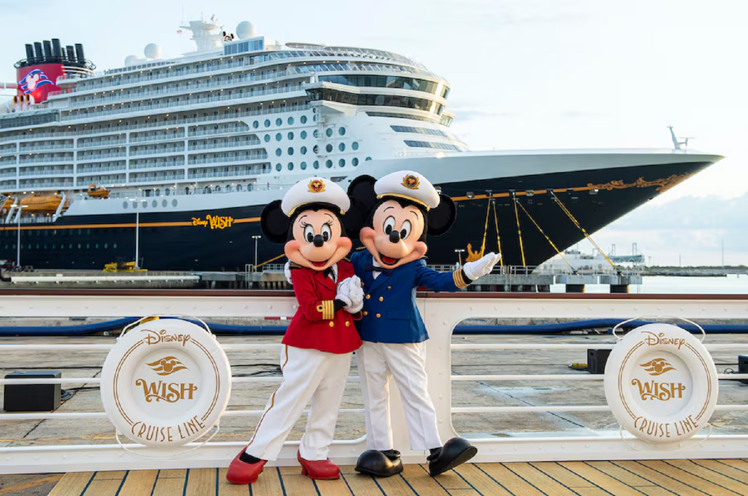 Mickey e Minnie com trajes de capitão em frente ao Disney Wish