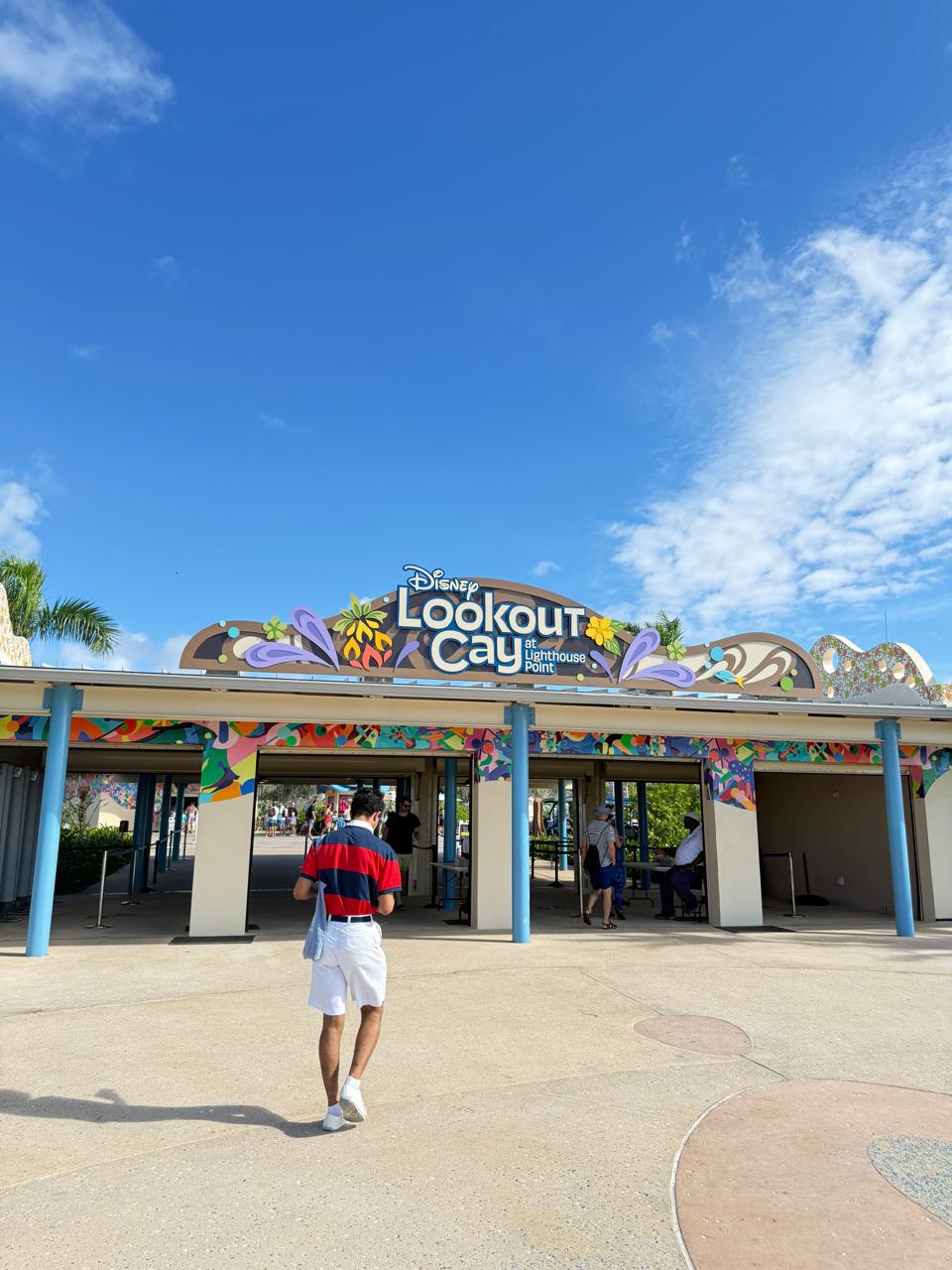 Entrada da ilha Disney Lookout Cay at Lighthouse Point nas Bahamas, com portal colorido e visitantes chegando à área exclusiva da Disney Cruise Line.